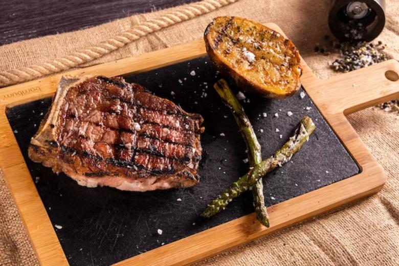 A perfectly grilled rump steak on a white plate.