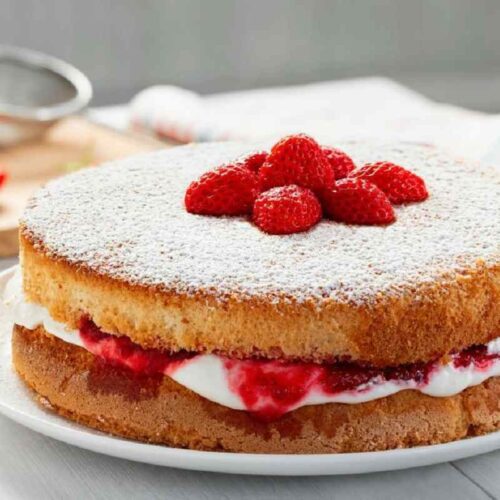 Freshly baked Victoria Sponge cake with layers of cream and berries.