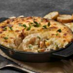 A delectable fish pie with a golden-brown crust, loaded with a medley of fresh seafood and creamy mashed potatoes.