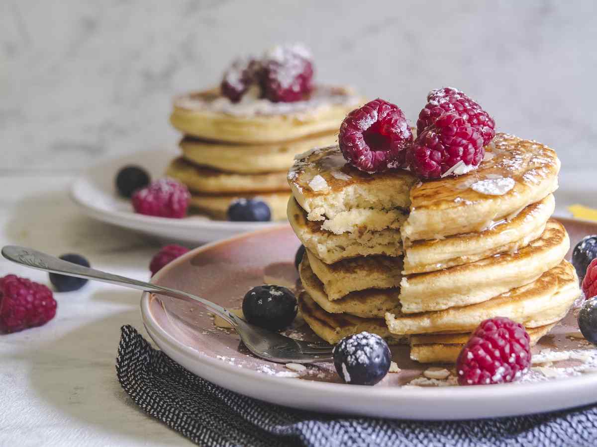 Stack of fluffy pancakes topped with whipped cream